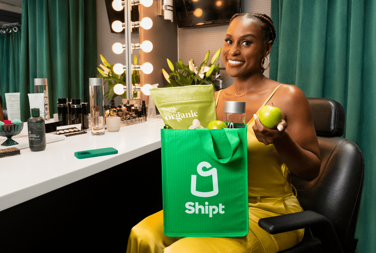 Issa Rae holding a green Shipt bag grocery delivery in her dressing room