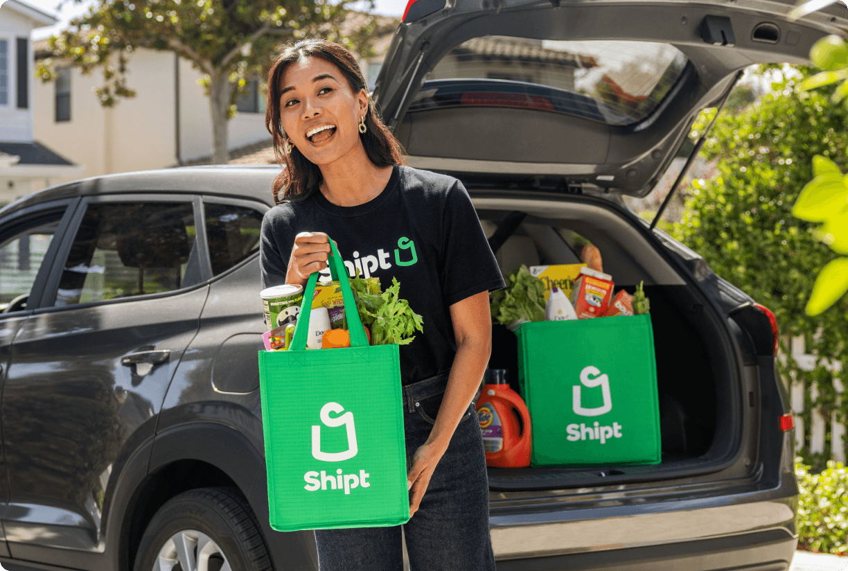 Shopper unloading Shipt delivery from trunk of car